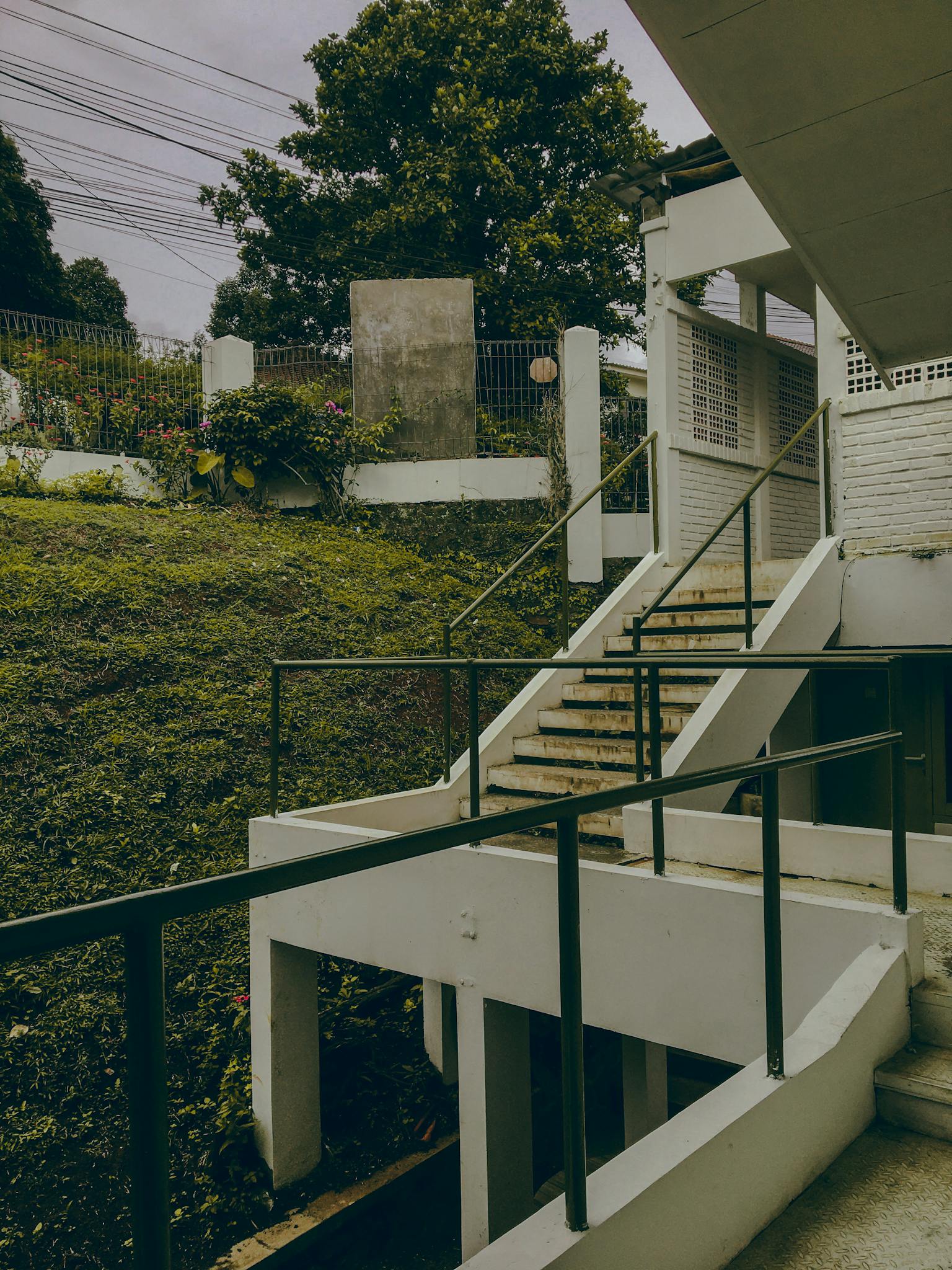 A contemporary outdoor staircase with railings and greenery in Jawa Barat, Indonesia.
