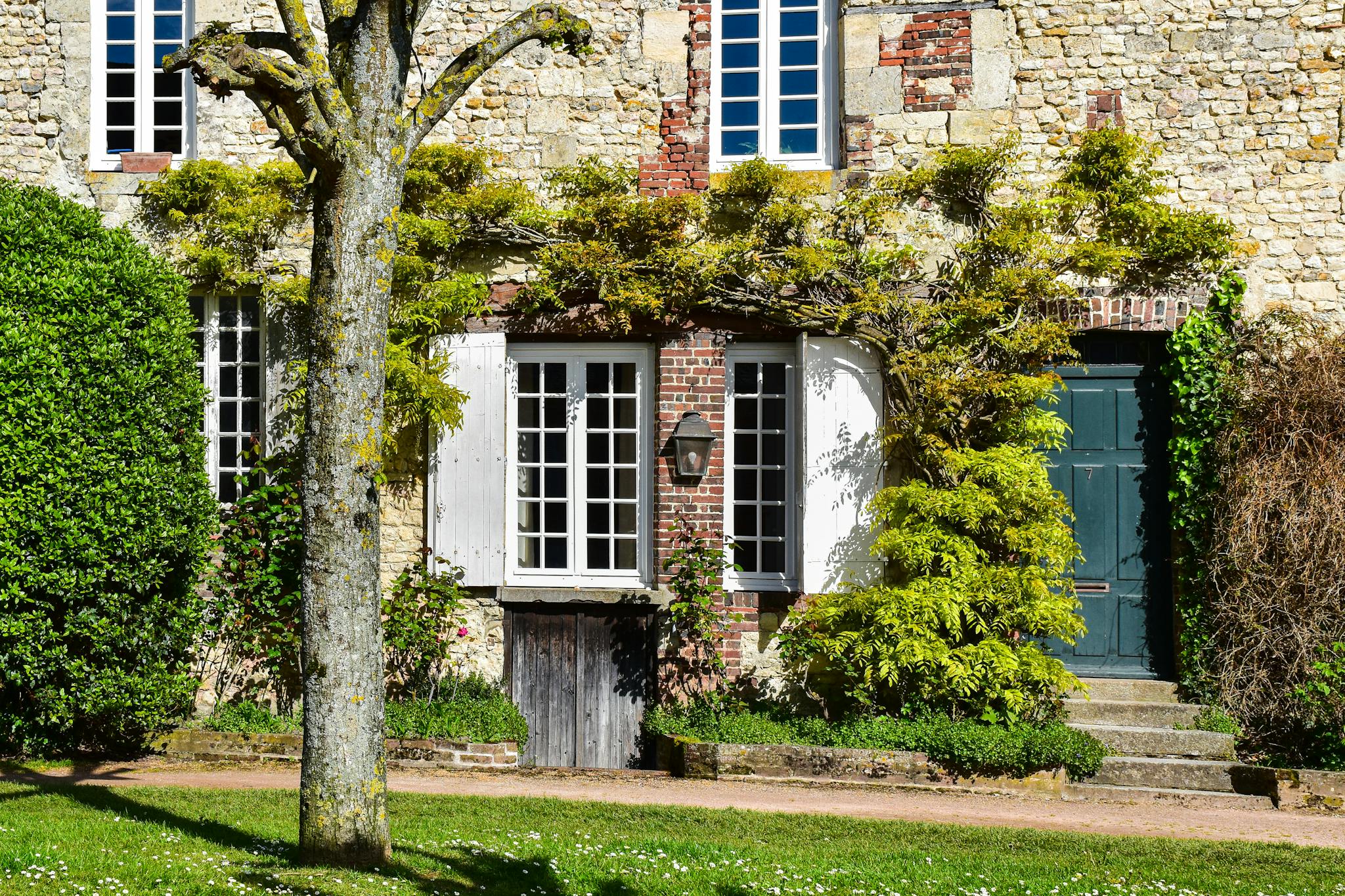 Charming stone facade with lush greenery in French countryside setting.